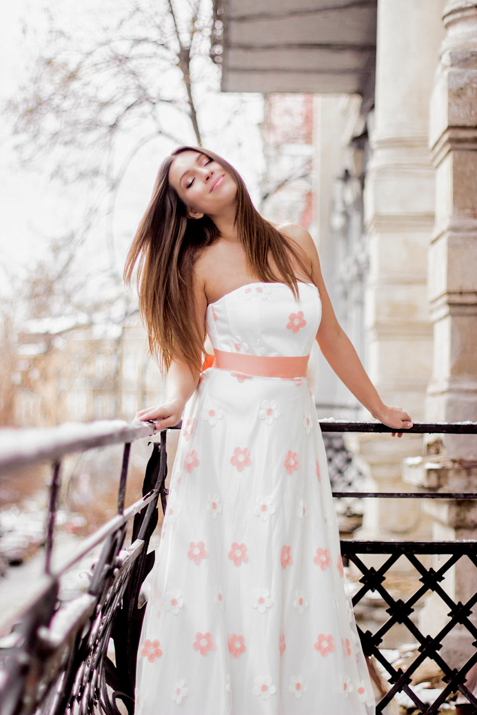 Happy woman in spring dress posing on balcony