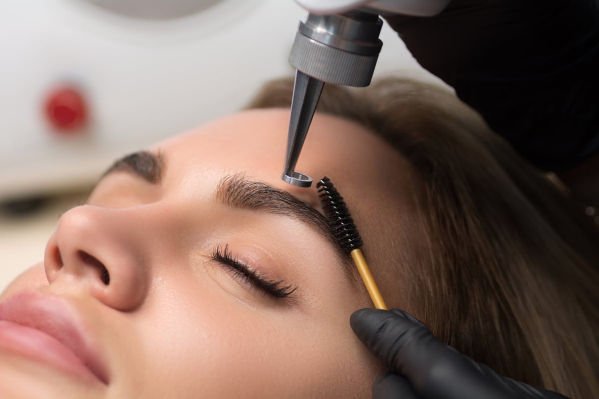 Laser removal of permanent makeup. The beautician removes the tattoo from the eyebrows